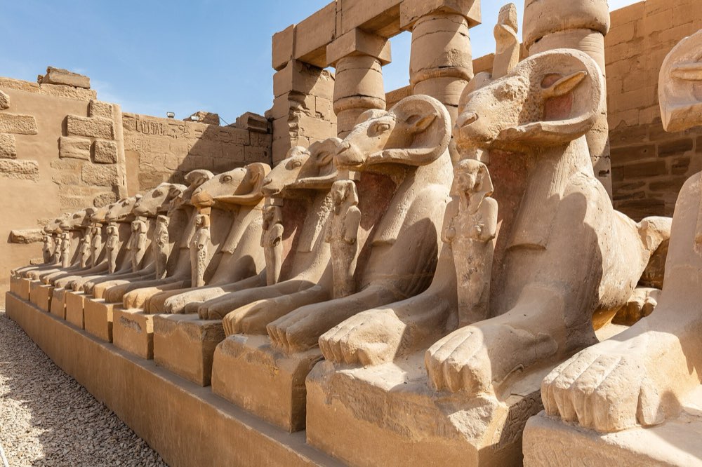 A row of ram-headed sphinx statues lining the avenue at Karnak Temple, Luxor